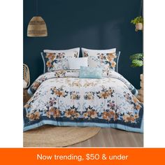 an image of a bed with blue walls and flowers on the comforter, which is now trending $ 50 & under