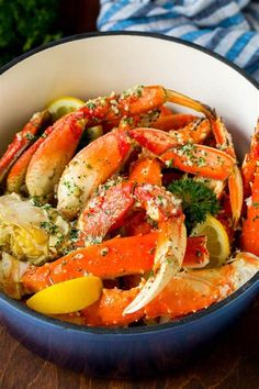 a bowl filled with cooked crabs and lemon wedges on top of a wooden table