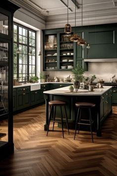 a large kitchen with green cabinets and wooden flooring, along with two bar stools