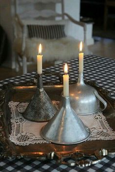 two silver vases on a tray with candles in them and some lace doily