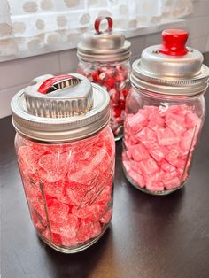 two glass jars filled with candy sitting on top of a table