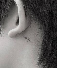 a person with a small tattoo on their left side behind the ear is wearing a pair of scissors