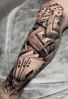 a man's arm with playing cards and dice tattoos on his arm, while he is