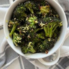 a white bowl filled with broccoli on top of a blue and white towel