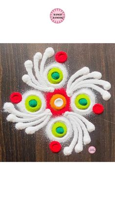 an image of a flower made out of white and red yarn on a wooden surface