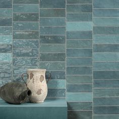 two vases sitting on top of a shelf in front of a blue tiled wall