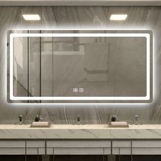 a bathroom with two sinks and a large mirror on the wall above it that is illuminated by lights