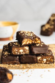 chocolate bars stacked on top of each other with nuts and oats scattered around them