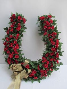 the letter o is made up of red roses and greenery with gold ribbons on it