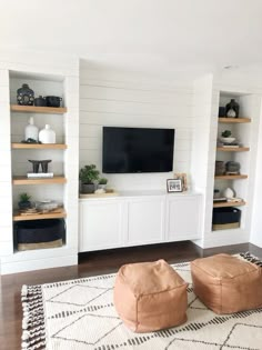 a living room with two bean bags on the floor and a large television mounted to the wall