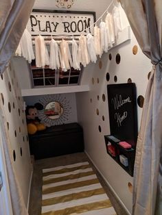 a room with polka dot curtains and a play room sign above the bed in it