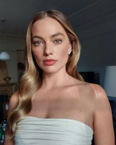 a woman with long blonde hair wearing a strapless white dress in a living room