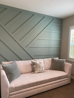 a white couch sitting in front of a window next to a wooden paneled wall