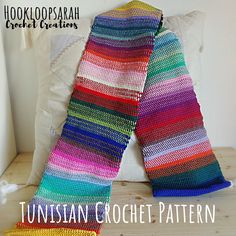 a colorful crocheted blanket sitting on top of a bed next to a pillow