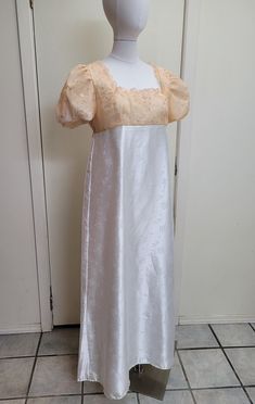 This dress has tracked shipping included within the US and Canada!    We offer a basic Regency styled gown, with the empire waist and short puffed sleeves.  The top of this dress has an apricot pink sheer overlay that has been embroidered with a scrolling design and tiny sequins.  The neckline has been trimmed with lace.  The skirt of the dress is a white satin jacquard with a dainty floral design.  Please check teh waist to hem measurement, as this is hemmed to a petite length.    *This gown ti Fitted Floor-length Gown For Fancy Dress, Cream Full-length Formal Dress, Formal Full-length Cream Dress, Fitted Floor-length Maxi Dress For Fancy Dress, Formal Full Length Cream Dress, Empire Waist Dress With Lined Bodice For Wedding, Empire Waist Wedding Dress With Lined Bodice, Cream Full Length Formal Dress, Elegant Empire Waist Costume Dress