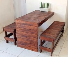 a wooden table and bench sitting next to each other on a tile floor in front of a door