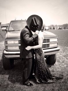 a man and woman standing next to each other in front of a truck wearing cowboy hats