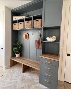 a mud room with gray cabinets and baskets on the shelves, white walls and floor