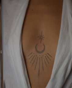 a woman with a cross and sun tattoo on her back shoulder, in white shirt