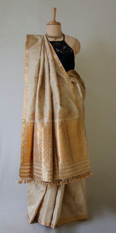 Made to Order Only This is a Handloom, Hundred Percent Pure Muga Silk Saree from the looms of ASSAM. The motifs are in golden tested zari .  This sari's pattern and the combination of only Muga and golden zari makes it a classic piece that will never go out of fashion .  Muga Silk - The most valued silk from India. Almost exclusively reared and produced in Assam, India. It is indigenous to the Brahmaputra Valley and assiduously practiced in the districts of Assam. The moth is basically a wild mo Luxury Handloom Tussar Silk Traditional Wear, Luxury Cotton Silk Saree, Luxury Bollywood Tussar Silk Fabric, Luxury Gold Tussar Silk Saree, Luxury Raw Silk Fabric With Embroidered Pallu, Luxury Handloom Tussar Silk Fabric, Luxury Handloom Katan Silk Traditional Wear, Gold Raw Silk Traditional Wear For Navratri, Gold Cutdana Traditional Wear For Festivals