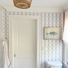 a white toilet sitting in a bathroom next to a wallpapered wall with fish on it