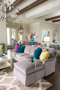 a living room filled with furniture and a chandelier hanging above the couches