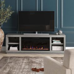 a living room with a fireplace and tv on the wall, in front of a blue painted wall