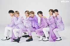 the group of young men are dressed in purple outfits and sitting on a white bench