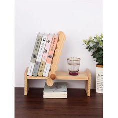 a small wooden chair sitting on top of a table next to a cup and plant