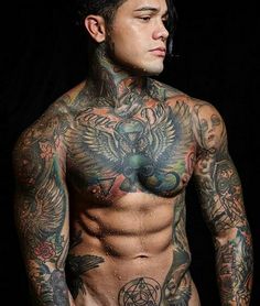 a man with lots of tattoos on his body and chest standing in front of a black background