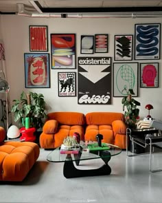 a living room filled with orange couches and pictures on the wall above them,