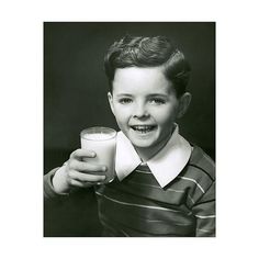 a black and white photo of a young boy holding a glass of milk