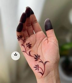 a woman's hand with a flower tattoo on her left thumb and fingers,