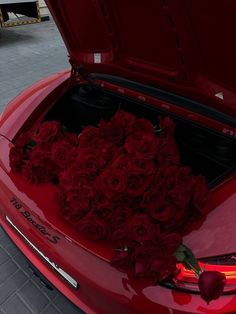 red roses are placed in the trunk of a car with it's hood open