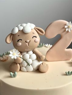 a cake decorated with a sheep and flowers on it's side, the number two is made out of fondant