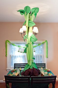 the table is set up for a party with green decorations and lights hanging from the ceiling