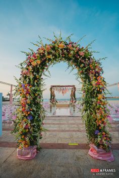 an archway decorated with flowers and greenery for a wedding ceremony at the beach side