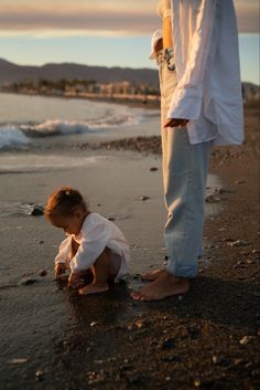 a little boy playing in the sand with his father at the ocean's edge