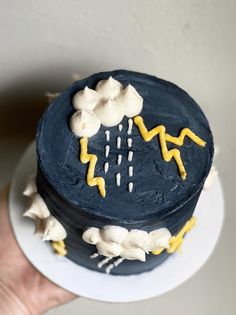 a hand holding a cake decorated with icing and lightning symbols on it's side