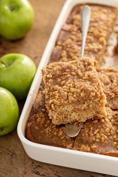 a close up of food in a pan on a table with apples and spoons