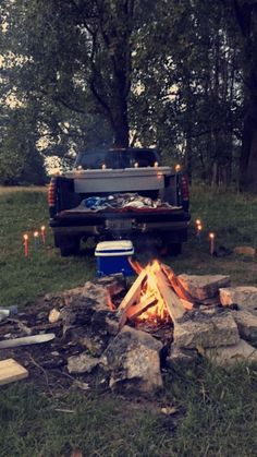 a truck is parked next to a campfire with candles in the bed and on the ground