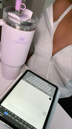 a woman holding a tablet next to a pink coffee cup