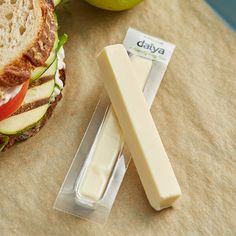 a sandwich sitting on top of a cutting board next to an apple and cheese knife