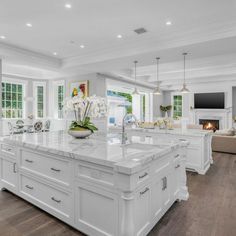 a large white kitchen with an island in the middle and lots of windows on both sides