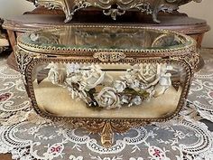 an ornately decorated box with flowers in it sitting on a doily covered table