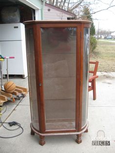 a wooden and glass display case sitting on the side of a house next to a basketball hoop