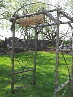 an arch made out of branches with a sign that says arches way on it in the grass