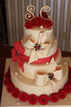 a three tiered wedding cake with red roses on the bottom and white icing