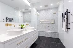 a white bathroom with two sinks and large mirrors on the wall next to each other