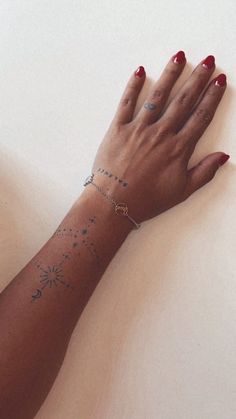 a woman's arm with tattoos on it and her hand resting on the table